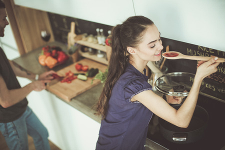 Couple cooking together in their kitchen at homeの写真素材