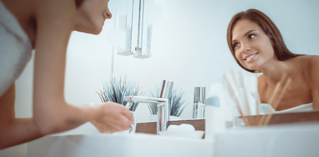 Young woman washing her face with clean water in bathroomの写真素材