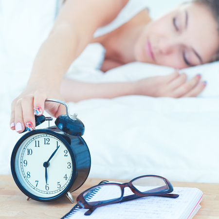 Beautiful young woman lying in bed comfortably and blissfullyの写真素材
