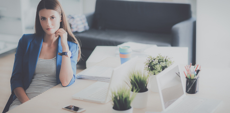 Woman sitting on the desk with laptopの写真素材