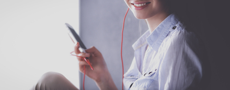 Smiling girl with headphones sitting on the floor near wallの写真素材