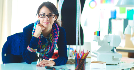 Beautiful fashion designer sitting at the desk in studioの写真素材