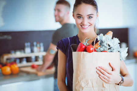 Young couple in the kitchen , woman with a bag of groceries shoppingの写真素材