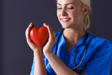 Doctor with stethoscope holding heart, isolated on gray backgroundの写真素材
