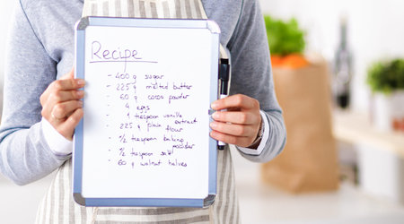 Woman in the kitchen at home, standing near desk with folderの写真素材