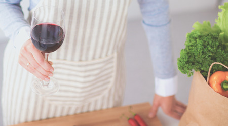 Pretty woman drinking some wine at home in kitchenの写真素材