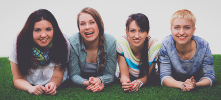 Four young women lying on green grassの写真素材