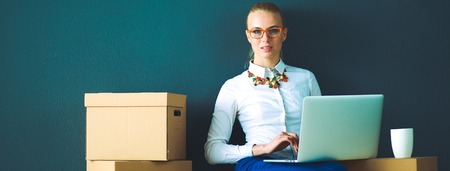Woman sitting on the floor near a boxes  with laptopの写真素材