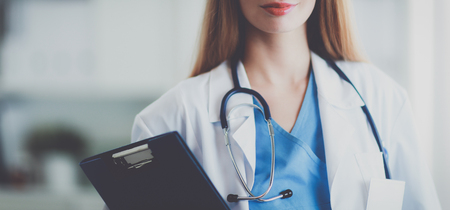 Portrait of woman doctor with folder at hospital corridorの写真素材