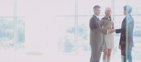 Business woman standing in foreground with a tablet in her handsの写真素材
