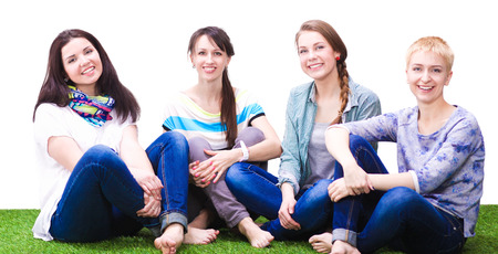 Four young women sitting  on green grassの写真素材