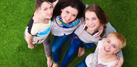 Four young women standing on green grass