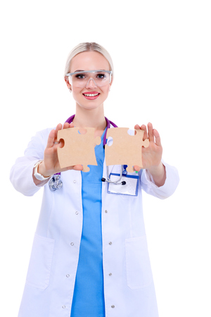 Woman doctor holding two connecting puzzle piecesの写真素材