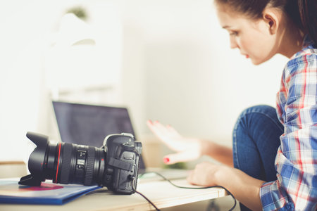 Female photographer sitting on the desk with laptop . Female photographer