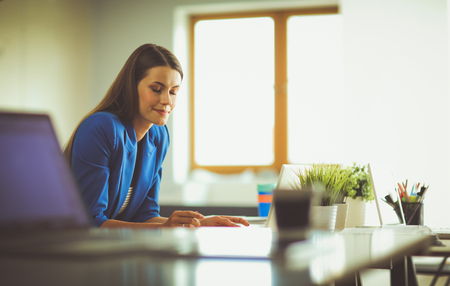 Woman sitting on the desk with laptop.の写真素材