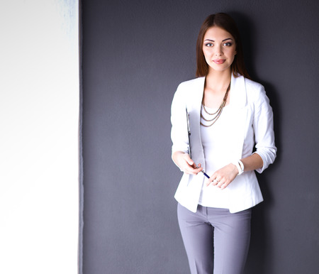 Young woman holding a laptop, standing on gray backgroundの写真素材