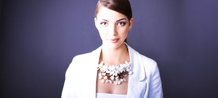 Portrait of young woman with beads, standing on gray backgroundの写真素材