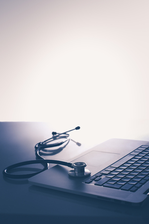 Workplace of doctor with laptop and stethoscope and notebook on white tableの写真素材