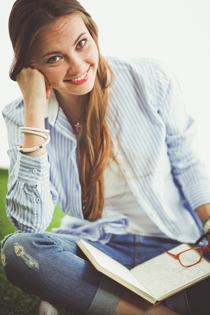 Young woman sitting with book on grass . Young womanの写真素材