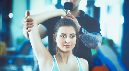 Beautiful woman at the gym exercising with her trainerの写真素材
