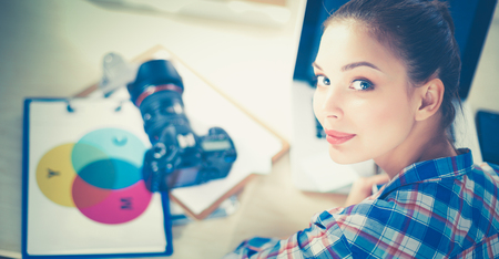 Female photographer sitting on the desk with laptopの写真素材