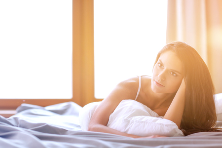 Beautiful brunette lying on bed at homeの写真素材