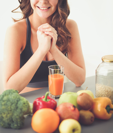Girl sitting in kitchen on the desk with fruit and glasses with juice.の写真素材