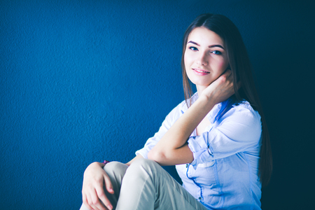 Young woman sitting on the floor near dark wallの写真素材