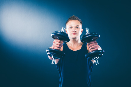 Handsome muscular man working out with dumbbellsの写真素材