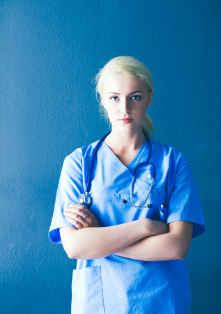 Portrait of smiling doctor in uniform standing on gray backgroundの写真素材