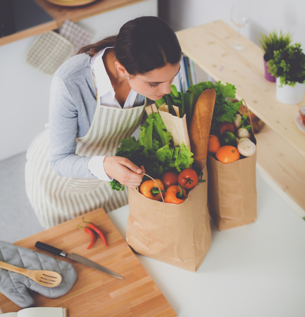 Woman with shopping bags in the kitchen at home, standing near deskの写真素材