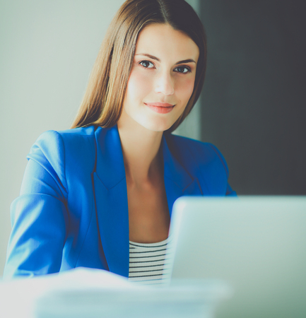 Woman sitting on the desk with laptopの写真素材