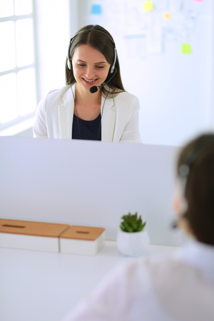Smiling businesswoman or helpline operator with headset and computer at officeの写真素材