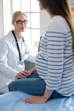 Beautiful smiling pregnant woman with the doctor at hospitalの写真素材