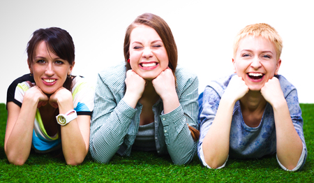 Four young women lying on green grassの写真素材