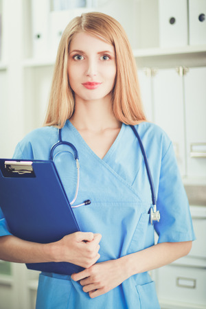 Portrait of woman doctor with folder at hospital corridorの写真素材