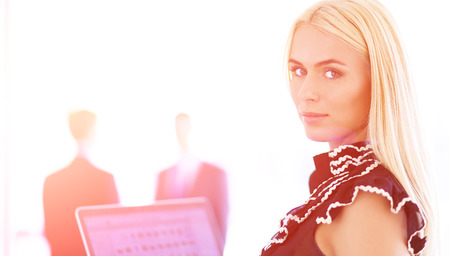 Young businesswoman holding a laptop, standing on officeの写真素材