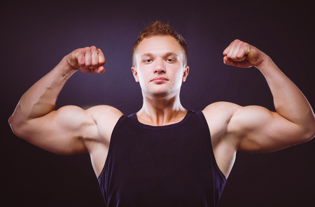 Strong and handsome young bodybuilder demonstrate his muscles and bicepsの写真素材
