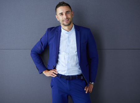 Young business man standing isolated on grey backgroundの写真素材