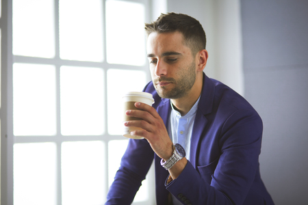 Attractive young man with smartphone on color backgroundの写真素材