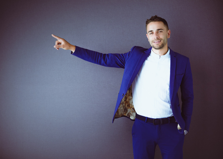Young business man standing isolated on grey backgroundの写真素材