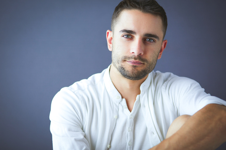 Young businessman sitting isolated on grey backgroundの写真素材