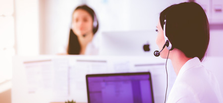 Smiling businesswoman or helpline operator with headset and computer at officeの写真素材
