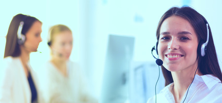 Smiling businesswoman or helpline operator with headset and computer at officeの写真素材