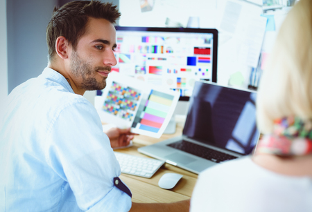 Portrait of young designer sitting at graphic studio in front of laptop and computer while working online.の写真素材