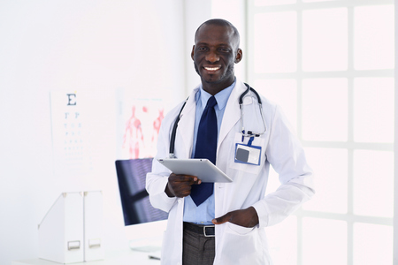 Male black doctor worker with tablet computer standing in hospitalの写真素材