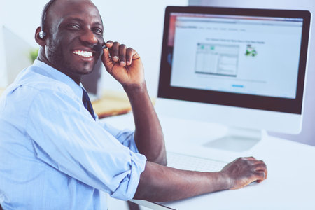 African american businessman on headset working on his laptop
