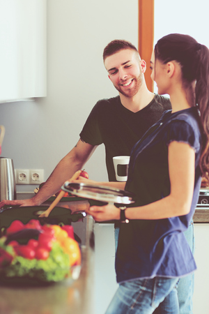 Couple cooking together in their kitchen at homeの写真素材