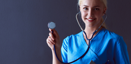Doctor listening with a stethoscope, close-up, isolated on grey backgroundの写真素材