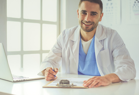 Male doctor using a laptop, sitting at his deskの写真素材